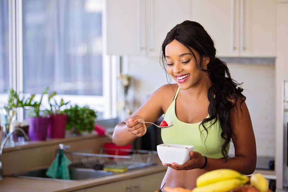 Smiling woman eating a nutritious fruit bowl in a bright kitchen setting